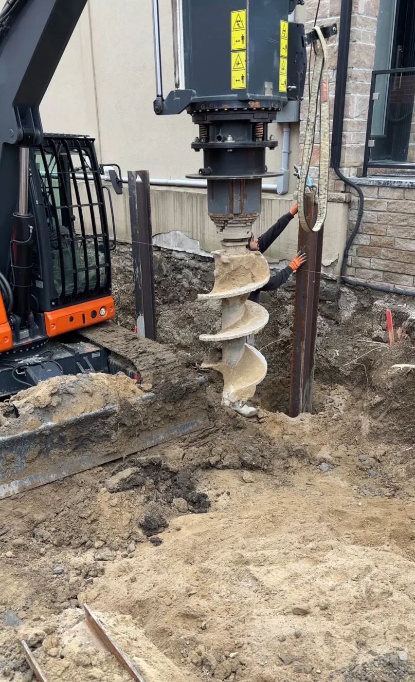 Auger and steel supports being installed at a residential excavation